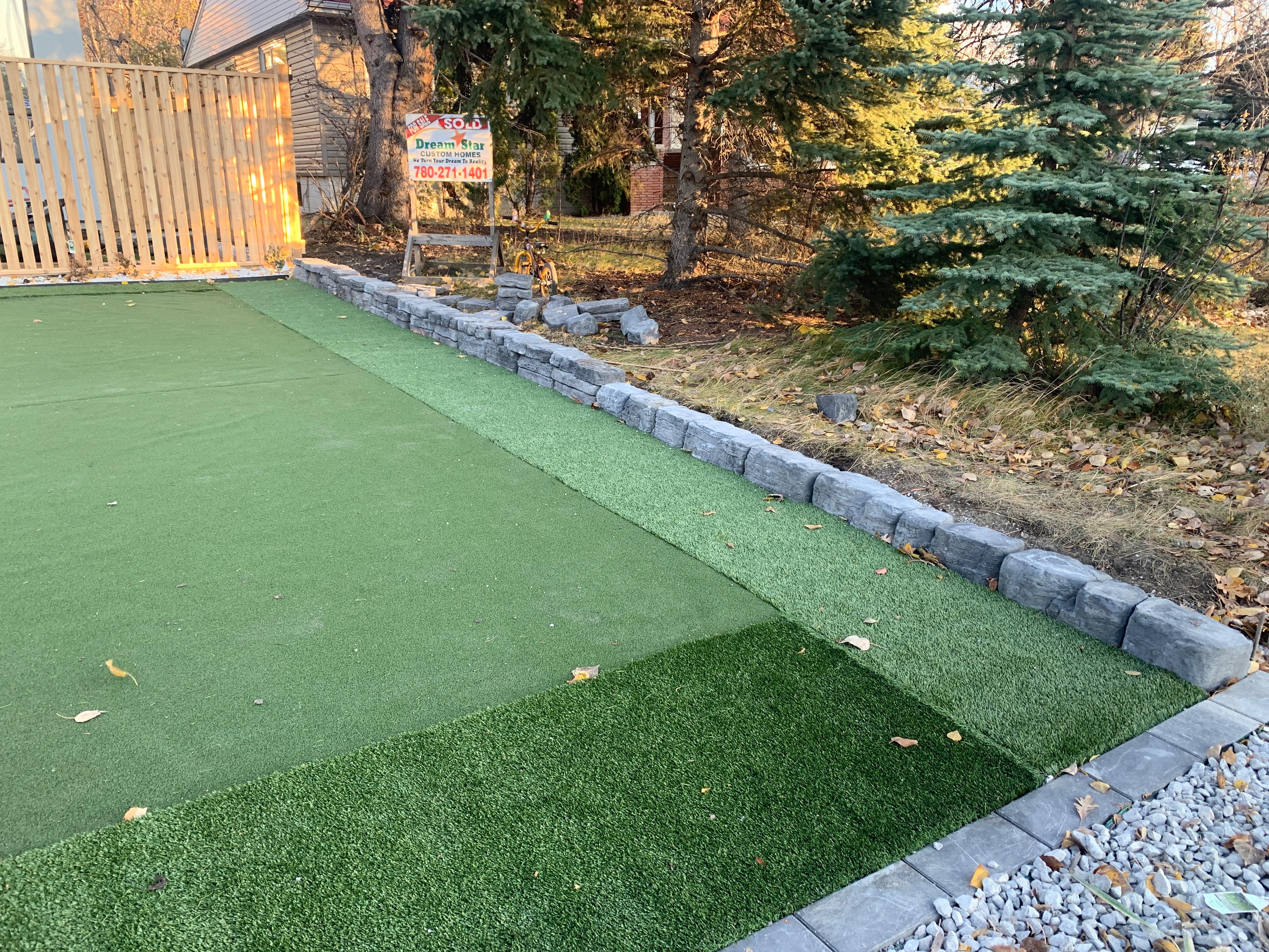 Artificial turf putting green sections with stacked stone retaining wall border
